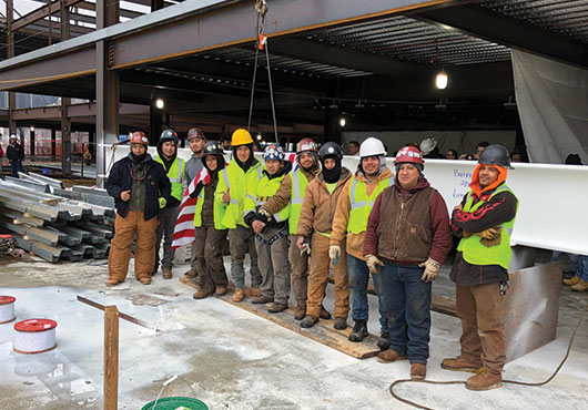 The Barone Steel Fabricators, Inc. crew celebrates the installation of the final beam in the project for Lexus of Manhattan to add six floors on the car dealership’s existing four-story structure.
